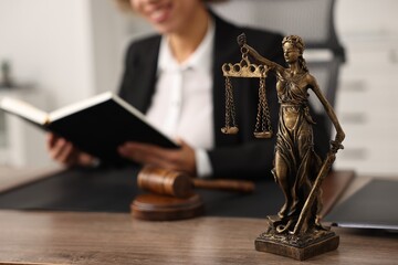 Notary with notebook at workplace in office, focus on statue of Lady Justice