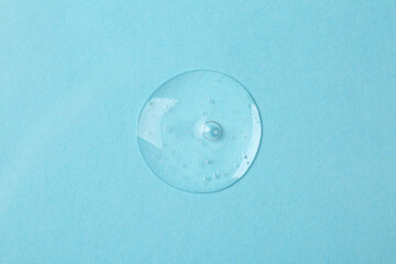 Sample of cosmetic serum on light blue background, top view