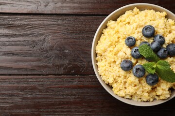 Tasty millet porridge with blueberries and mint in bowl on wooden table, top view. Space for text
