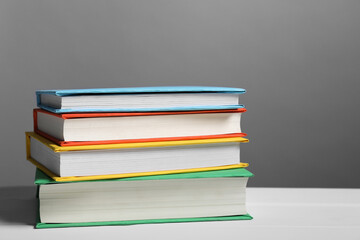 Different books on white table against gray background. Space for text