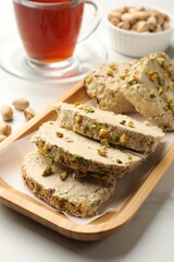 Tasty halva with pistachios served on white marble table, closeup
