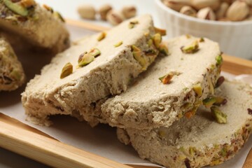 Tasty halva with pistachios on table, closeup