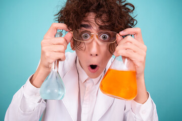 A funny doctor conducts chemical experiments with liquids. A man with test tubes. The study of the interactions of substances. Blue background.