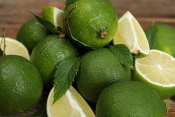Pile of fresh wet limes and leaves on table, closeup
