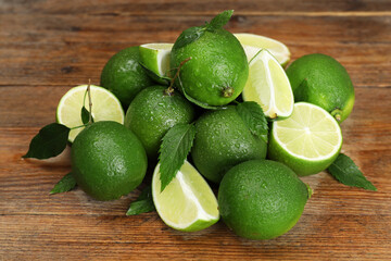 Pile of fresh wet limes and leaves on wooden table