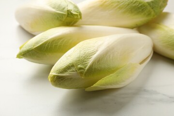 Raw ripe chicories on white marble table, closeup