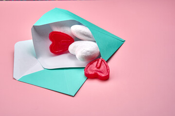 Blue envelope with two heart lollipops inside. The envelope is on a pink background, representing love and tenderness.