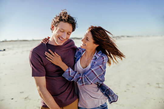 Cheerful couple embracing and walking on the beach