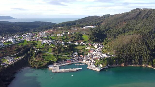 Beautiful aerial landscape in North of Spain, Galicia. Typically costal small village, surrounded by forest. Small bay of water. O Vicedo village. Fishing boats. Drone tracking right.