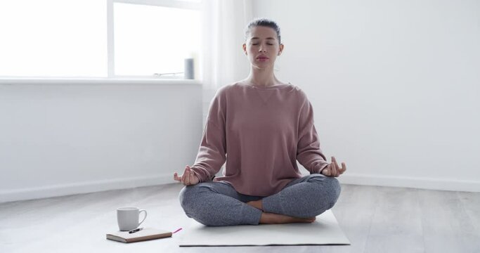 Yoga, woman and namaste on floor with breathing for meditation, wellness and mindfulness with coffee in home. Person, mat and peace on ground for zen, healthy body or relaxing in living room of house