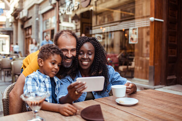 Fototapeta na wymiar Multicultural Family Sharing a Smartphone at an Urban Cafe