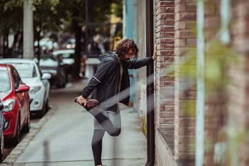 Young male runner stretching before city jog