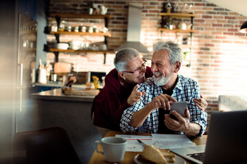 Senior Couple Laughing and Looking at Smartphone in home