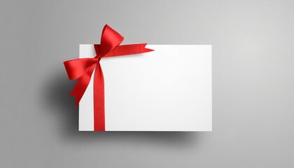 blank white gift card with red ribbon bow isolated on grey background with shadow minimal conceptual