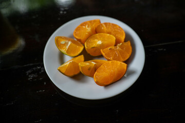 white plate filled with cut orange slices ready to make orange juice with citrous