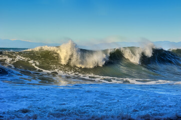 powerful great waves on the sea crests with foam, mountains in the distance on the horizon