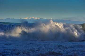 the great waves, lit by the sun, of the Sea rolling up, mountains on the horizon