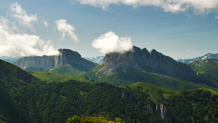 High majestic cliffs in the clouds. Two cliffs with a long steep precipice. View from the air. Mountains Chertovy Vorota. Travelling to wild, beautiful places of the planet.