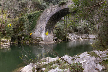 Roman stone bridge over river with clear water and rocky banks