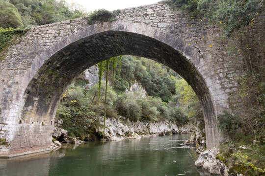 Roman stone bridge over river with clear water and rocky banks
