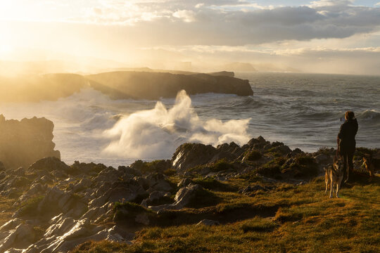 Woman taking a picture of the ocean coastline at Bufones de Pria in Asturias north of Spain on a windy day with rough sea