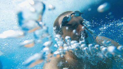 Snorkelling in the sea. A man with goggles on his head in the water among many bubbles. He has just...