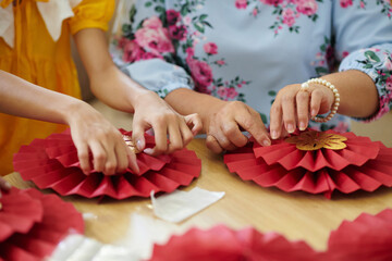 Hands of family members making paper decorations for spring festival