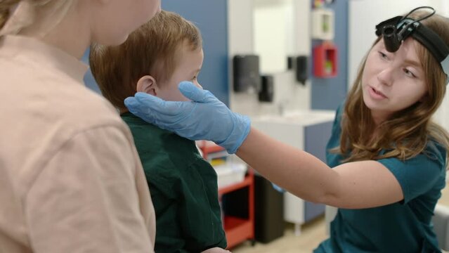 A cute toddler boy with his mother are at an appointment with a pediatric ENT to prepare for kindergarten. The doctor otolaryngologist is establishes contact and trust with the little patient