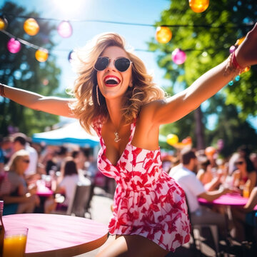 Mujer rubia riendo de pie con los brazos extendidos con gafas de sol y un vestido corto blanco y rojo en una terraza veraniega