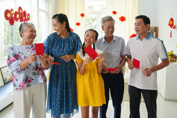 Joyful Vietnamese family with lucky money red envelopes - obrazy, fototapety, plakaty