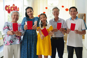 Happy three generation family showing lucky money envelopes, as traditional gift for Tet