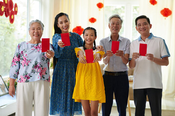Big Vietnamese family showing lucky money envelopes as traditional gift for Spring festival