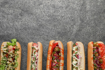Delicious hot dogs with different toppings on grey table, flat lay. Space for text - obrazy, fototapety, plakaty