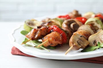 Delicious shish kebabs with vegetables and microgreens on white table, closeup