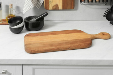 Wooden cutting boards and other cooking utensils on white countertop in kitchen