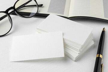 Blank business cards, glasses and pen on white table. Mockup for design