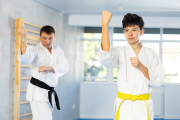 Fototapeta na wymiar Karate trainer teaching block and punches to a teenager in the gym