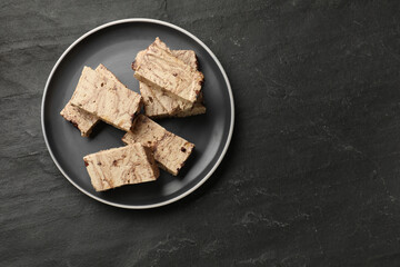 Tasty chocolate halva on black table, top view. Space for text