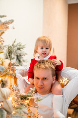 Young father man and baby child toddler have fun  at home in front of the Christmas tree, New Year's home decor. Festive family atmosphere. 