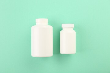 Blank white pill bottles on turquoise background, top view. Space for text