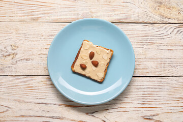 Toast with tasty nut butter and almonds on light wooden table, top view