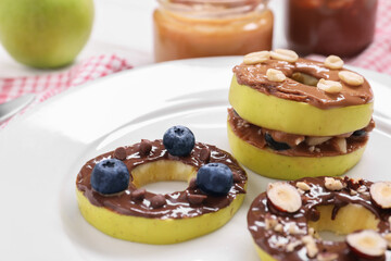 Fresh apples with nut butters, blueberries and nuts on plate, closeup