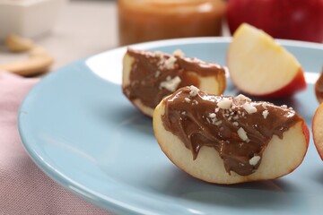 Slices of fresh apple with nut butter and chopped nuts on table, closeup