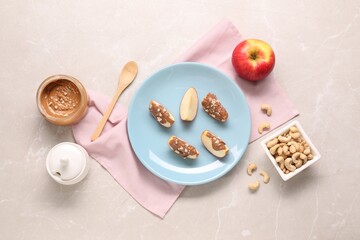 Slices of fresh apple with nut butter and cashews on light marble table, flat lay