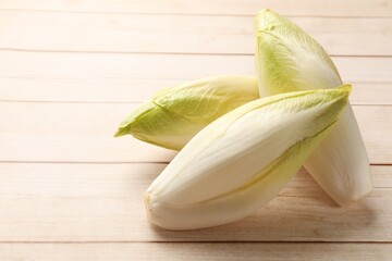 Raw chicories on wooden table, closeup. Space for text