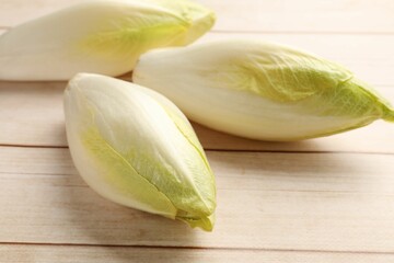 Raw ripe chicories on wooden table, closeup