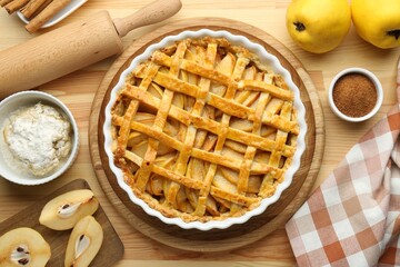 Tasty homemade quince pie and ingredients on wooden table, flat lay