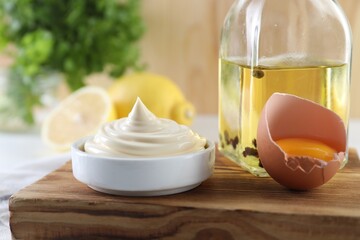 Fototapeta na wymiar Fresh mayonnaise sauce in bowl and ingredients on table, closeup