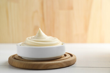 Fototapeta na wymiar Fresh mayonnaise sauce in bowl on white wooden table, space for text