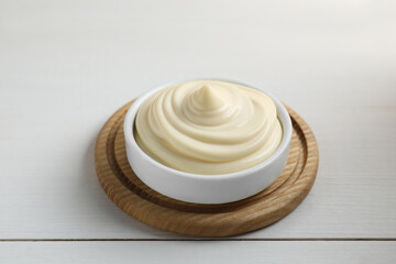 Fototapeta na wymiar Fresh mayonnaise sauce in bowl on white wooden table